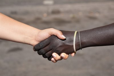 Twee mensen van verschillende etniciteiten schudden elkaar de hand, wat wederzijds respect en verbinding symboliseert.